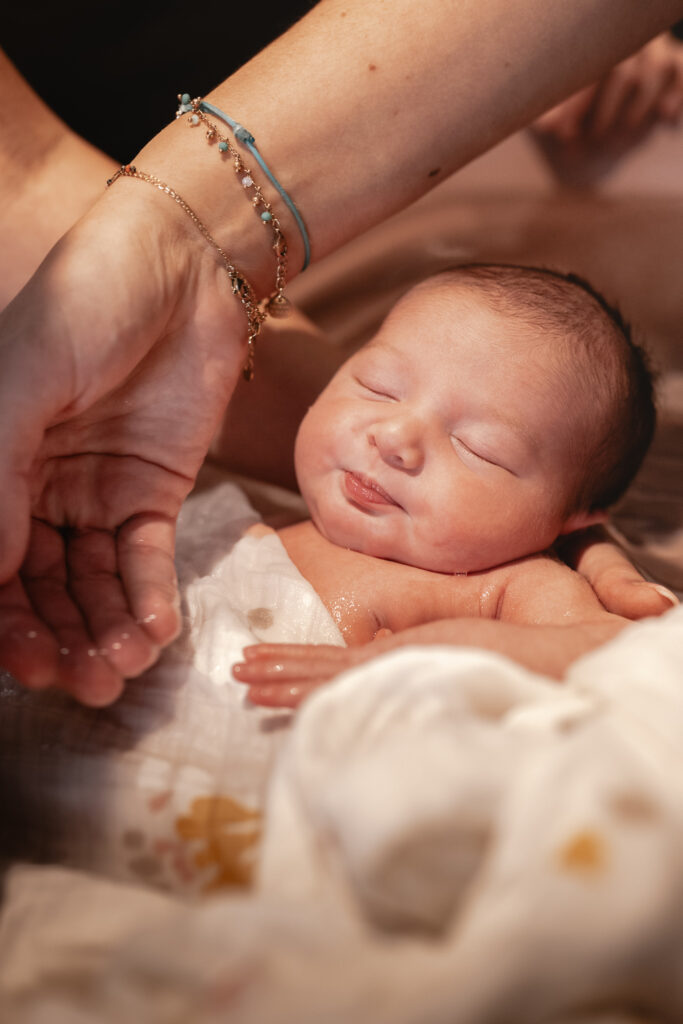 Séance photo naissance en studio à Morez : nouveau-né endormi dans les mains de sa maman, gros plan