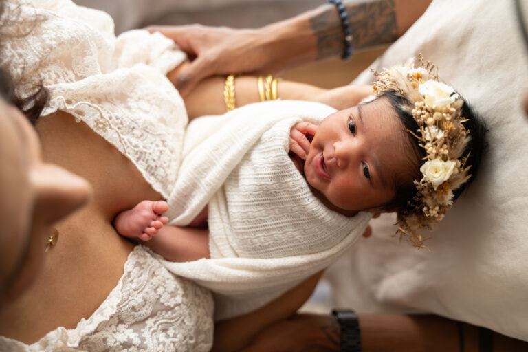 Séance photo naissance en studio à Morez : bébé endormi avec couronne de fleurs dans les bras de sa maman