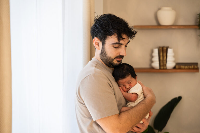 Séance photo naissance en studio à Morez : papa qui berce son nouveau-né contre lui
