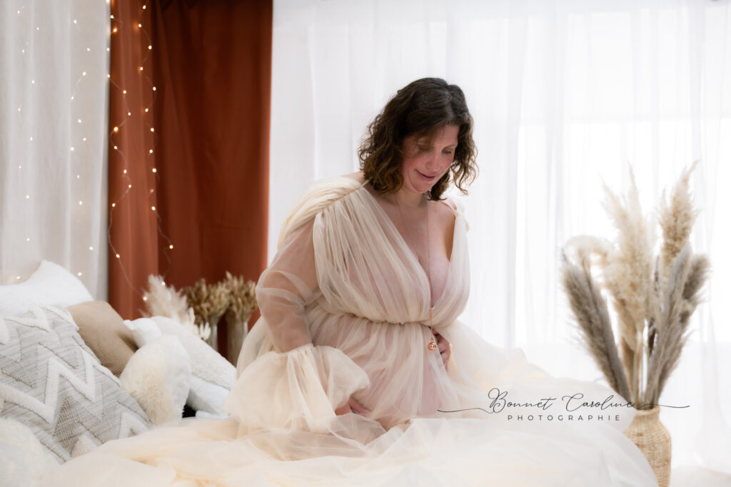 Séance photo grossesse en studio à Morez : future maman en robe rose au milieu des herbes de pampa