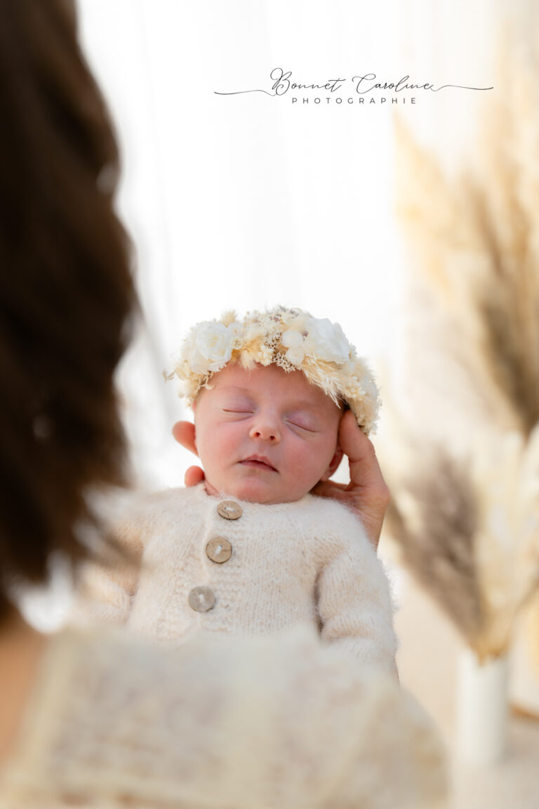Séance photo naissance en studio à Morez : nouveau-né endormi en tenue crème avec couronne de fleurs