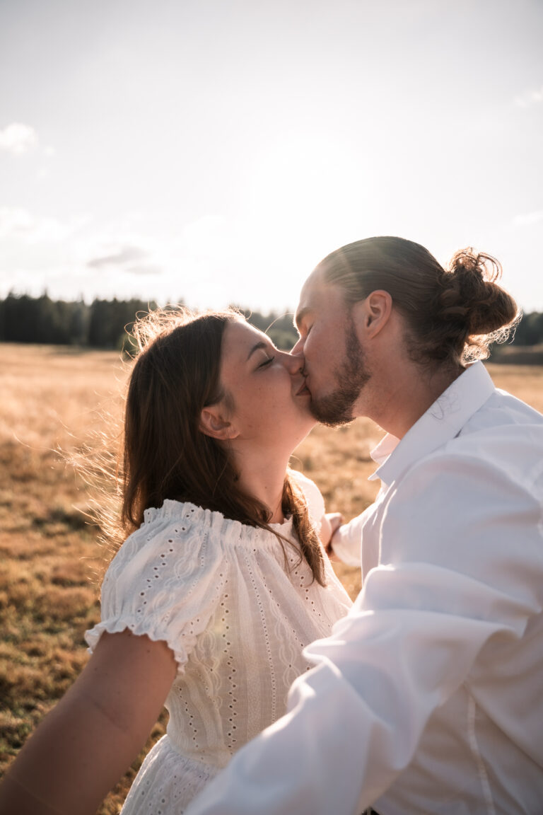 Séance photo couple dans le Jura : couple qui s’embrasse dans les herbes dorées