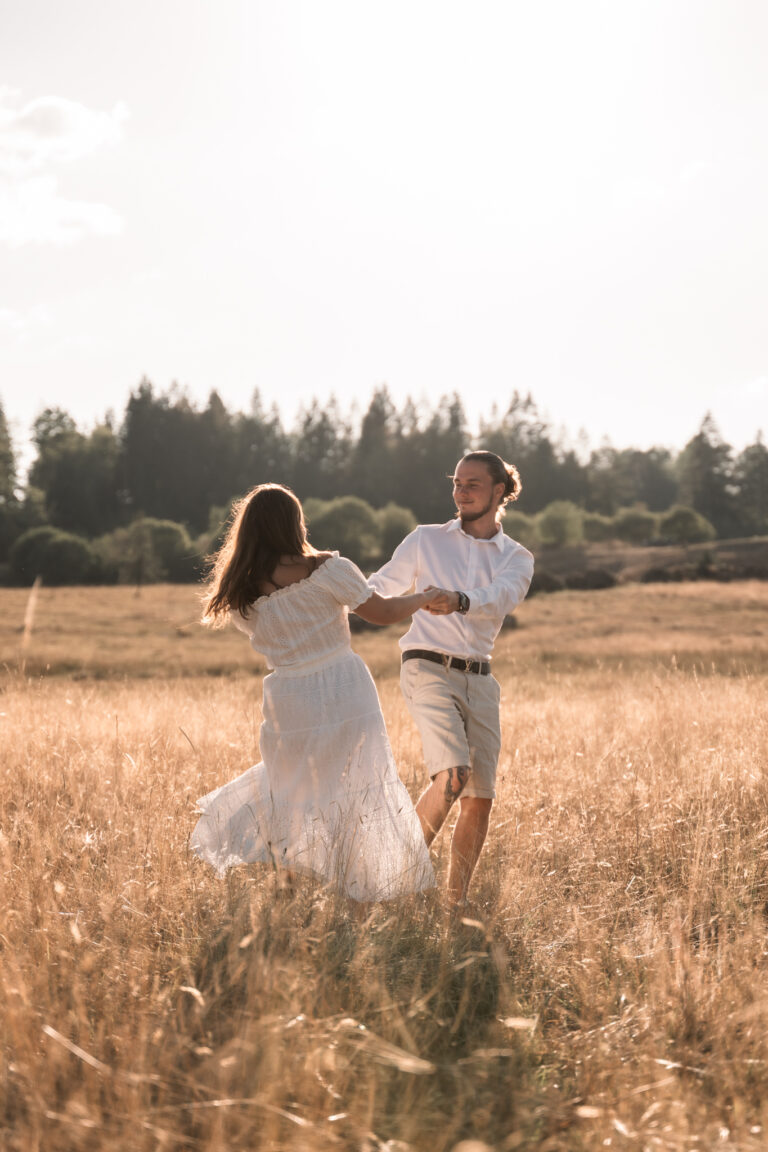 Séance photo couple dans le Jura : couple qui danse dans un champ au coucher du soleil