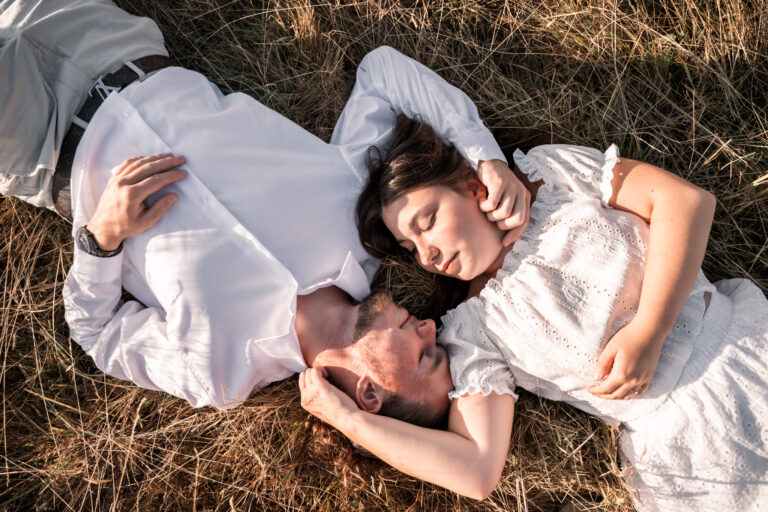 Séance photo couple dans le Jura : couple allongé dans l’herbe, tête-bêche, yeux fermés