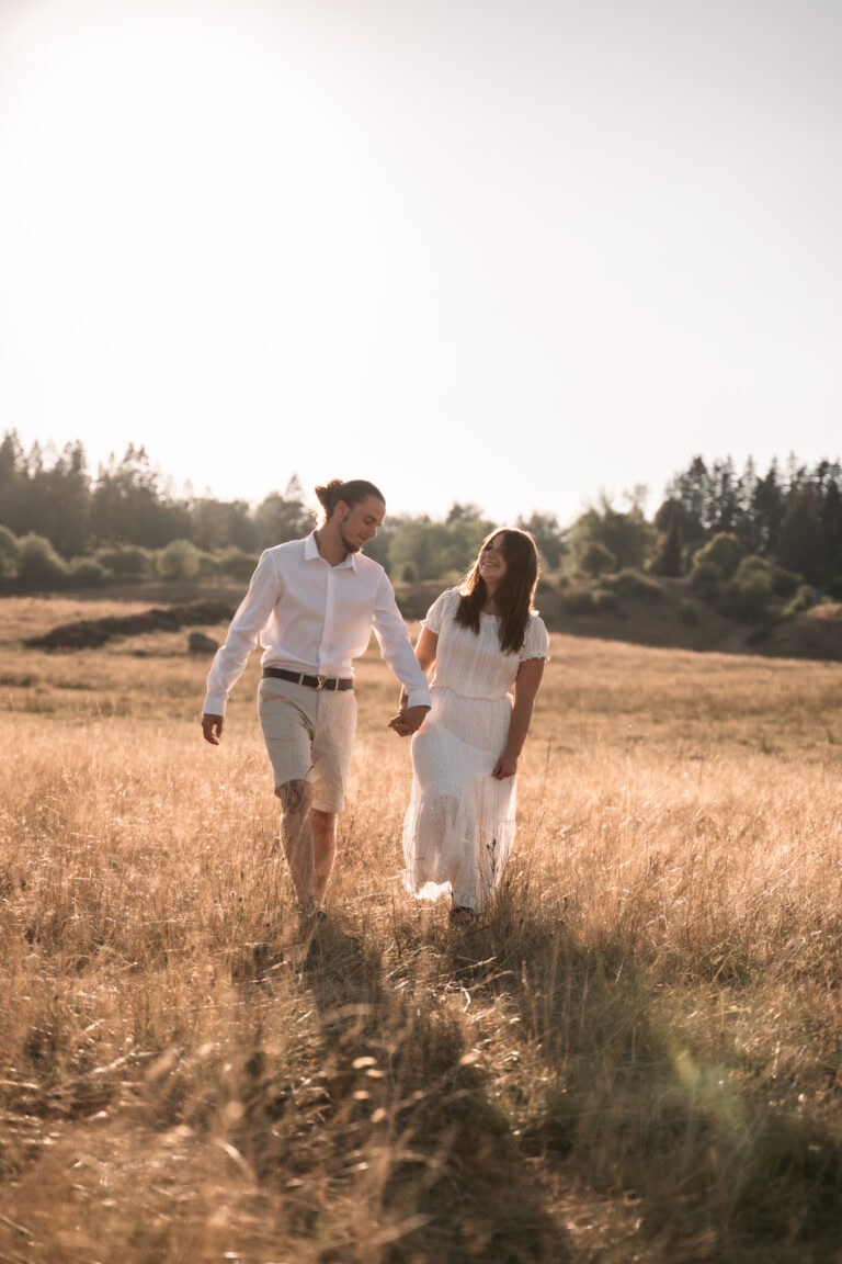 Séance photo couple dans le Jura : couple main dans la main dans les herbes hautes au soleil