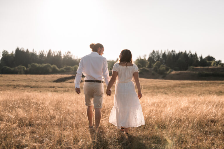 Séance photo couple dans le Jura : couple qui marche main dans la main dans un champ doré