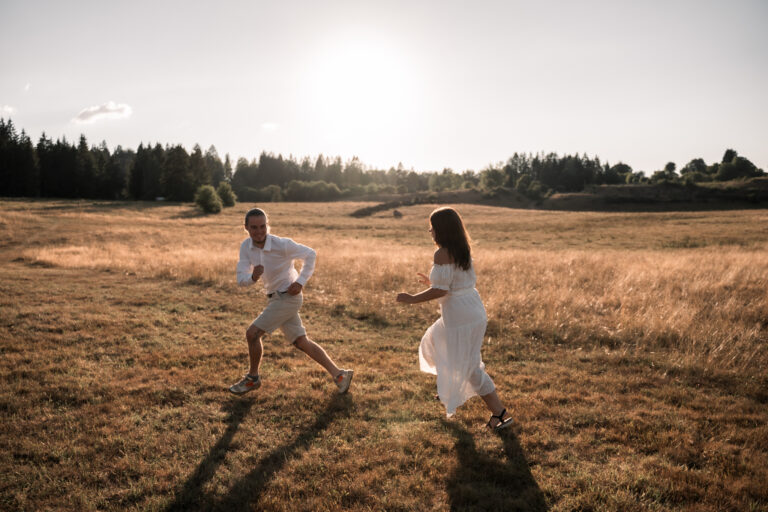 Séance photo couple dans le Jura : couple qui court dans un champ doré au coucher du soleil