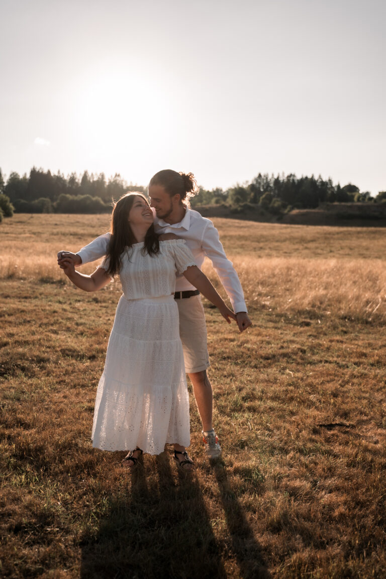 Séance photo couple dans le Jura : couple enlacé dans un champ, à contre-jour