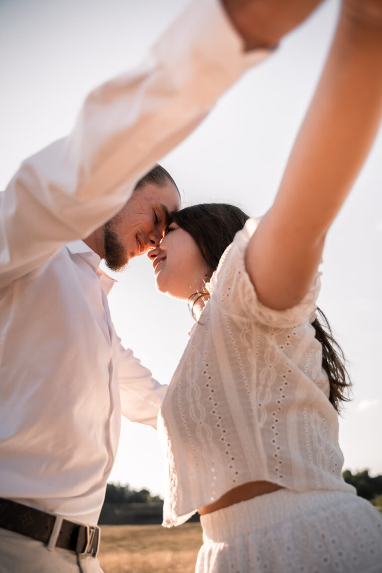 Séance photo couple dans le Jura : couple front contre front, bras levés vers le ciel