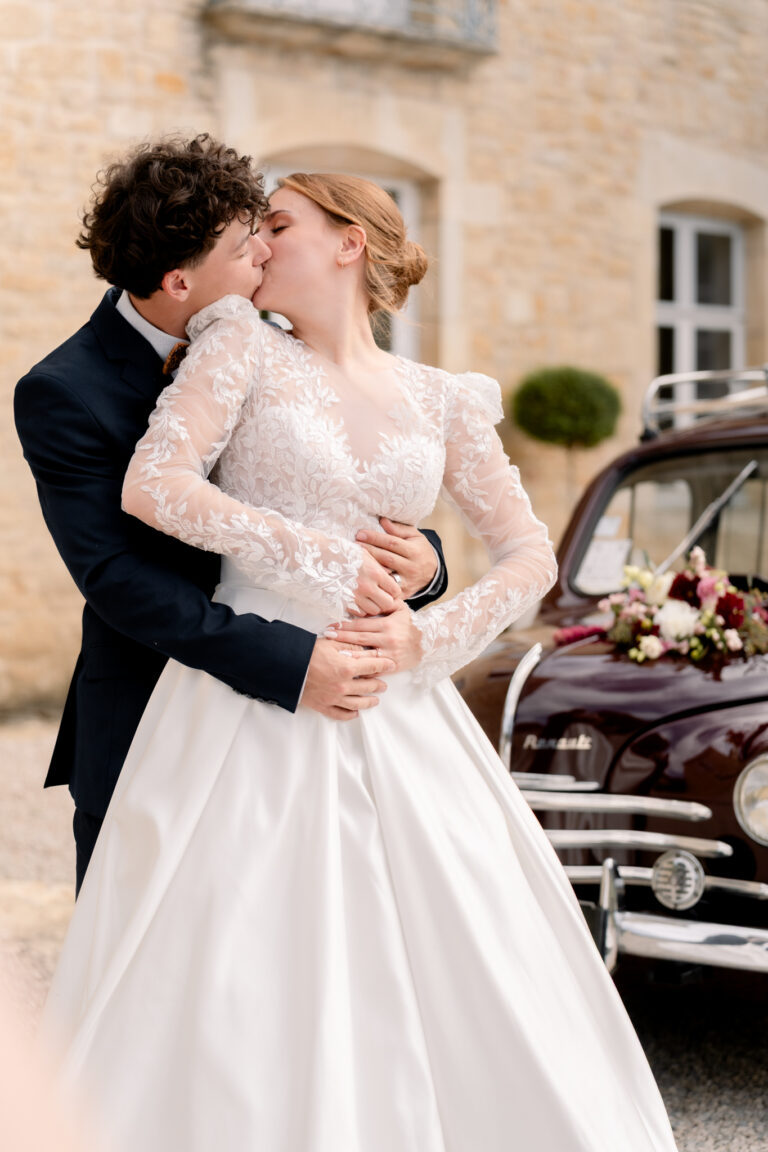 Photographe mariage Jura : marié qui embrasse sa mariée devant une voiture ancienne