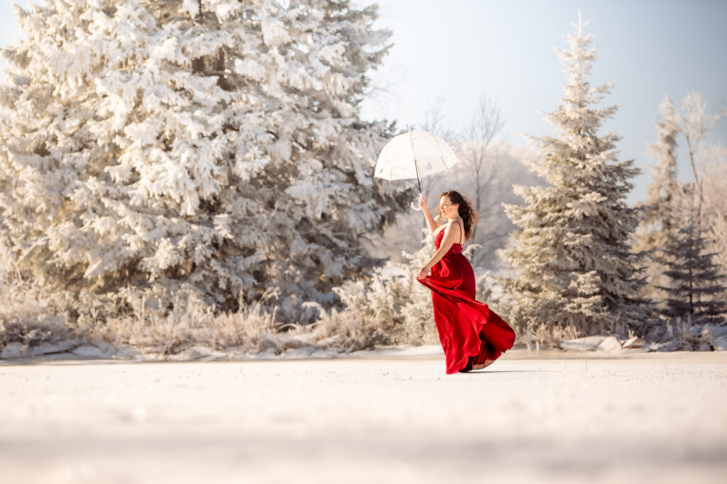 Photographe portrait Morez Jura Genève Lausanne Champagnole Lons-le-Saunier – femme en robe rouge avec une ombrelle au milieu des sapins givrés