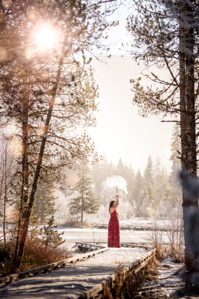 Photographe portrait Morez Jura Genève Lausanne Champagnole Lons-le-Saunier – femme en robe rouge sur une passerelle dans une forêt enneigée