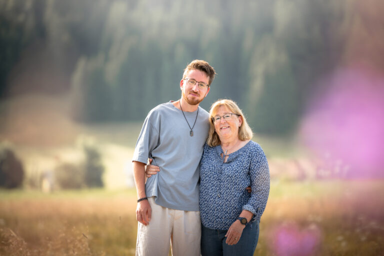 Séance photo famille dans le Haut-Jura : mère et son fils souriants côte à côte dans un pré fleuri
