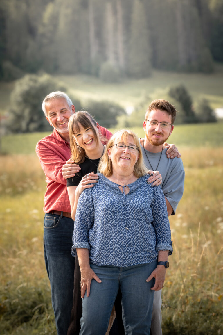 Séance photo famille dans le Haut-Jura : famille réunie dans un pré à la lumière du soir