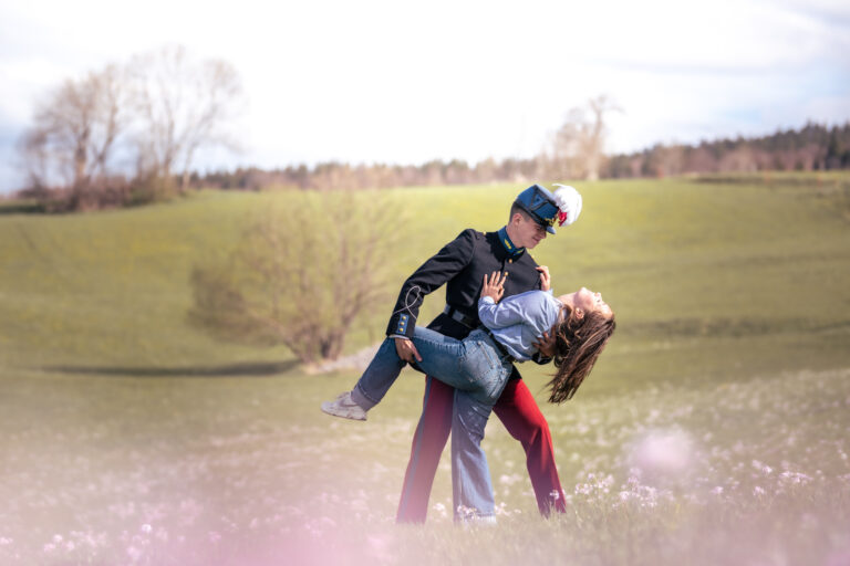 Photographe mariage couple Morez Jura Genève Lausanne Champagnole Lons-le-Saunier Besançon – homme en uniforme faisant tournoyer sa compagne dans un pré