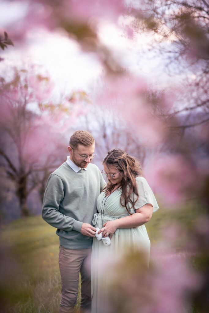 Photo de grossesse au printemps dans le Jura – couple regardant les chaussons de bébé