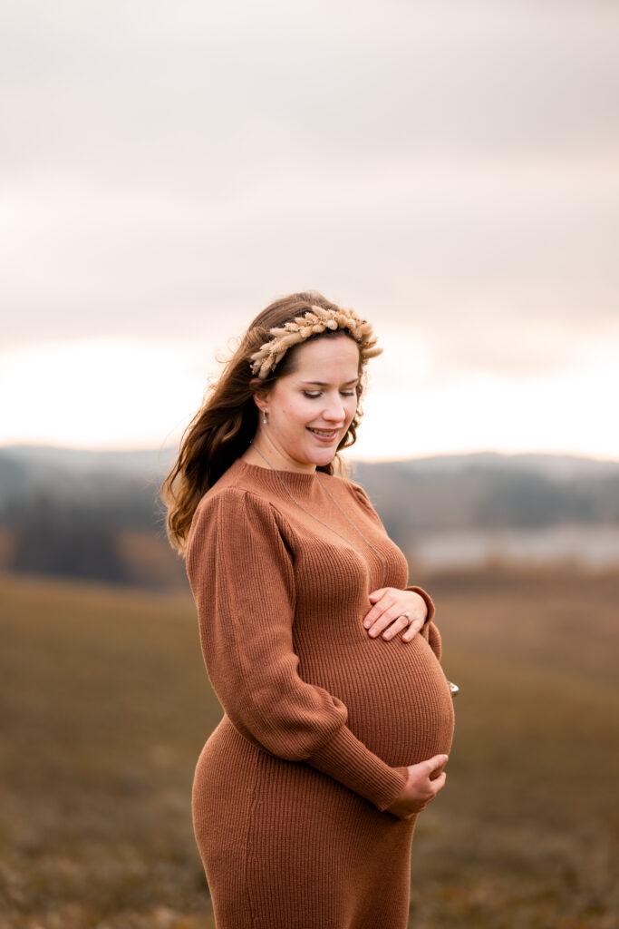 Photo de grossesse aux Rousses – future maman souriante, mains sur le ventre