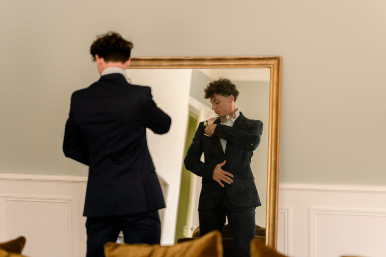Photographe mariage Jura : marié qui enfile sa veste devant le miroir