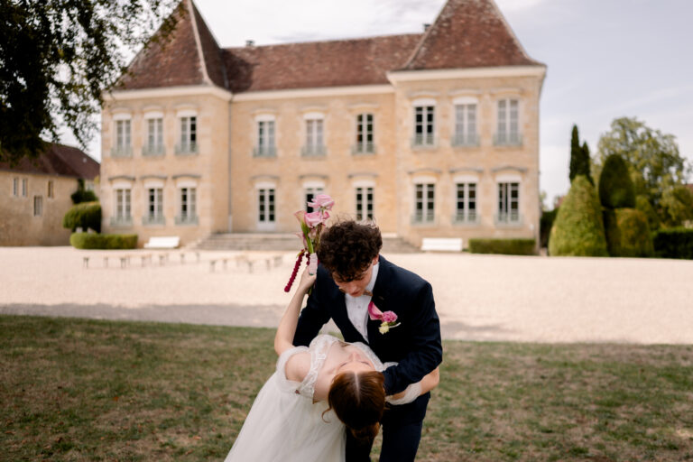 Photographe mariage Jura : marié qui fait basculer sa mariée devant le Château de Gevingey