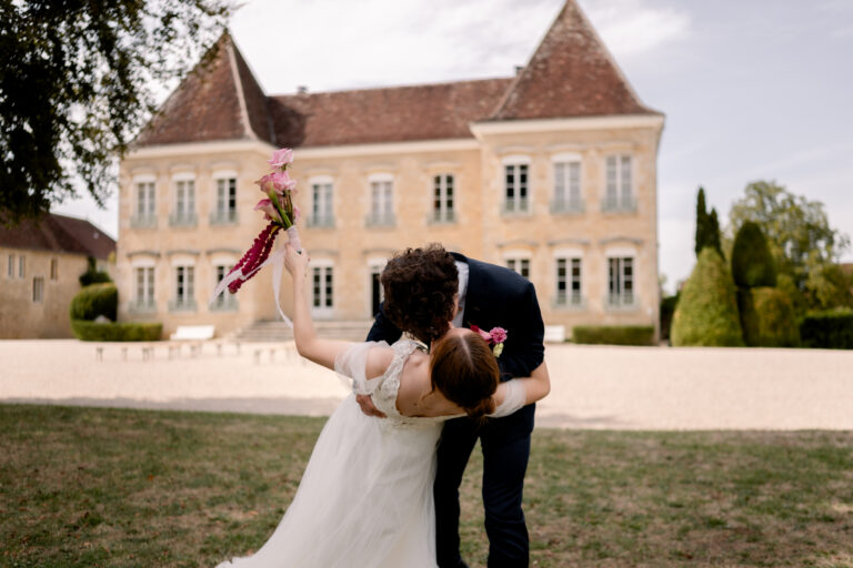 Photographe mariage Jura : marié qui fait basculer sa mariée devant le Château de Gevingey