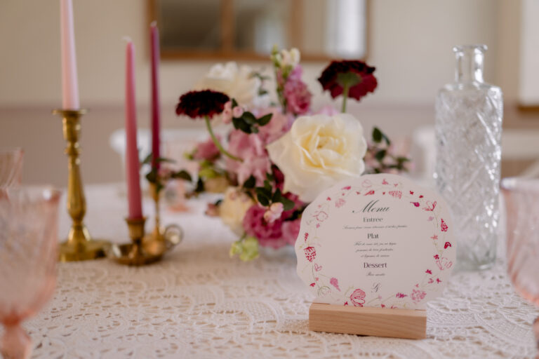 Photographe mariage Jura : table rose poudré avec bougies et marque-place en aquarelle