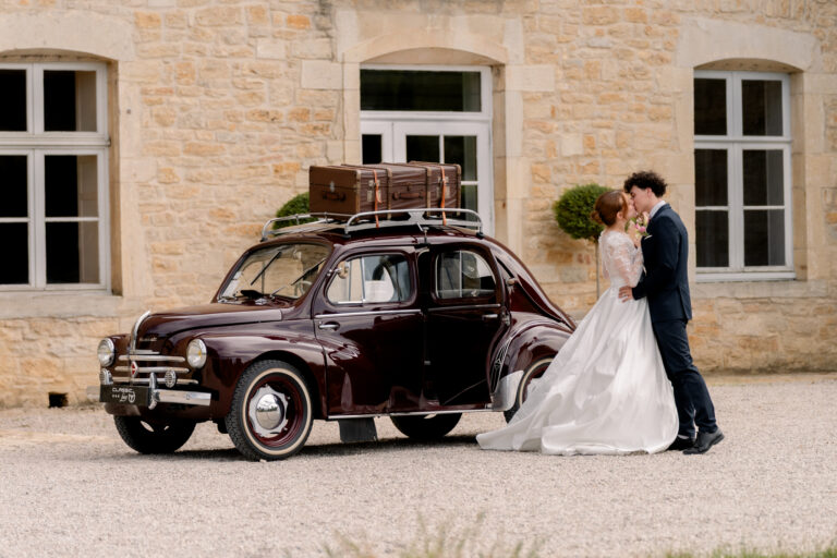 Photographe mariage Jura : mariés enlacés devant la voiture ancienne