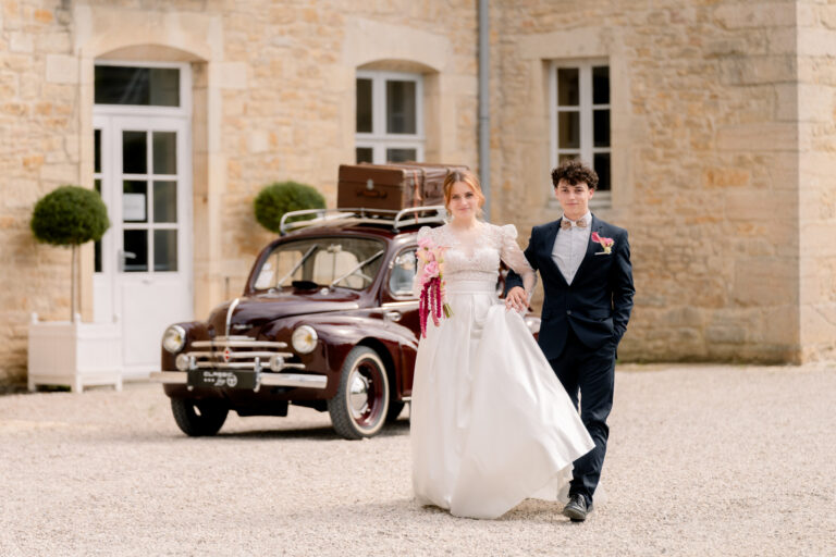 Photographe mariage Jura : mariés main dans la main devant la voiture ancienne