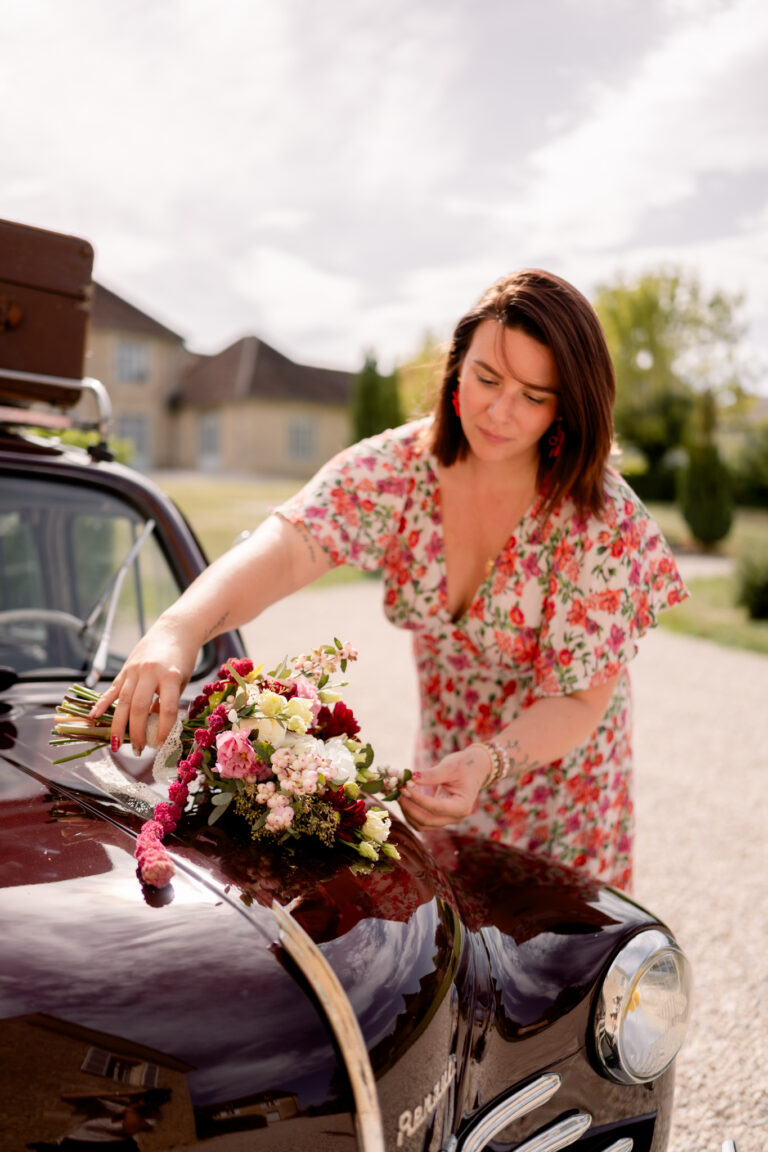 Photographe mariage Jura : fleuriste qui installe les fleurs sur la voiture ancienne