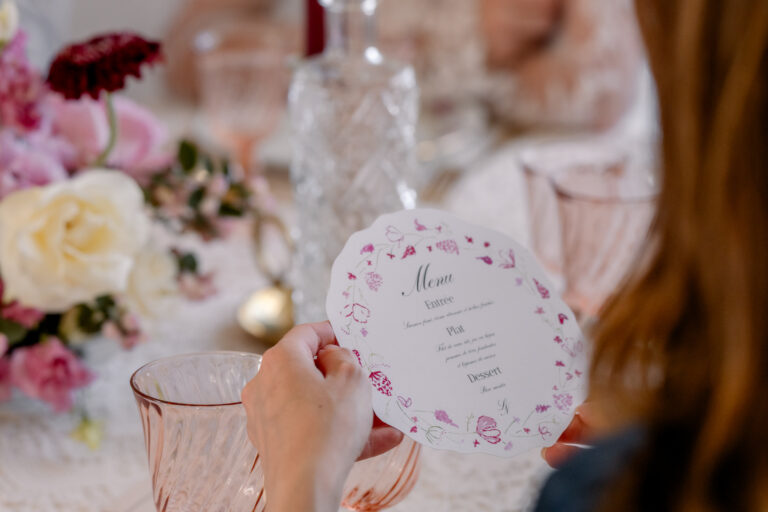 Photographe mariage Jura : menu aquarelle tenu à la main au-dessus de la table