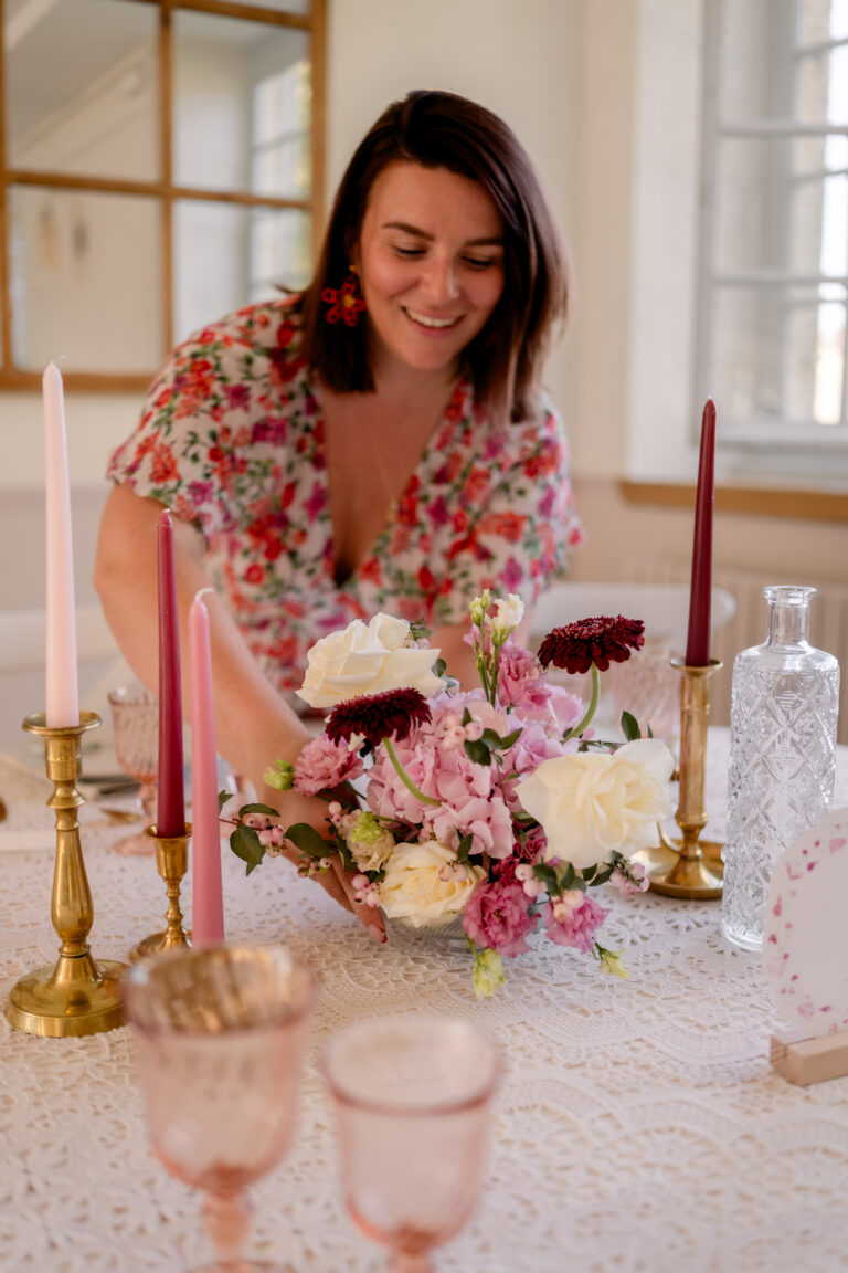 Photographe mariage Jura : fleuriste souriante qui installe le centre de table