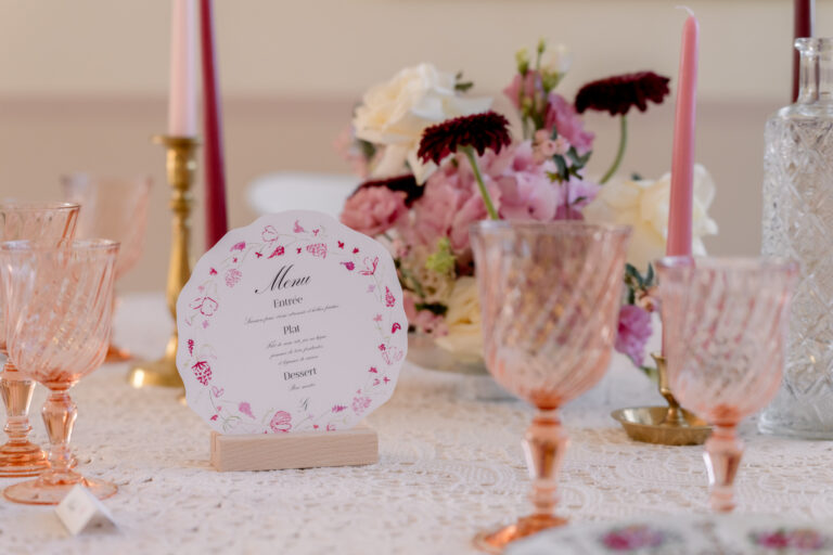 Photographe mariage Jura : table rose avec verres colorés et fleurs bordeaux