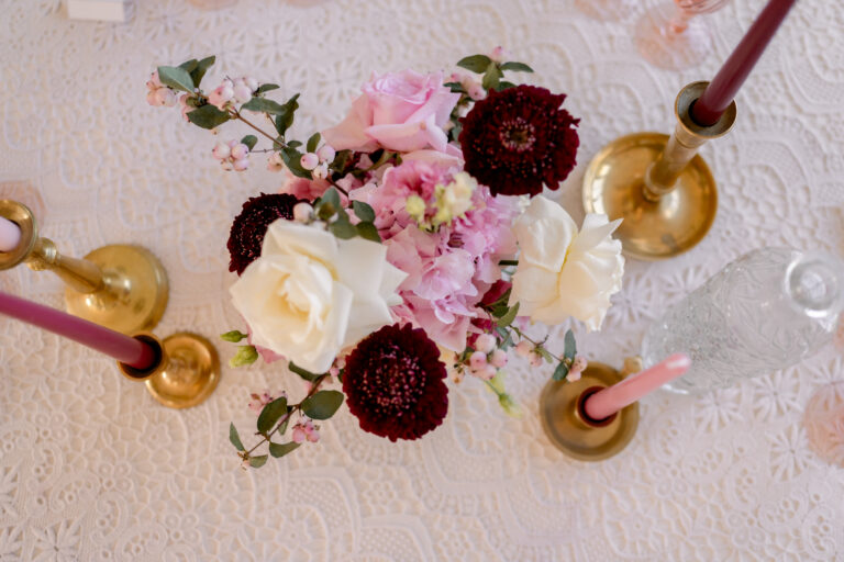 Photographe mariage Jura : centre de table en roses blanches et fleurs bordeaux, vu de dessus