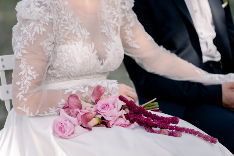 Photographe mariage Jura : détail de la robe en dentelle et main du marié