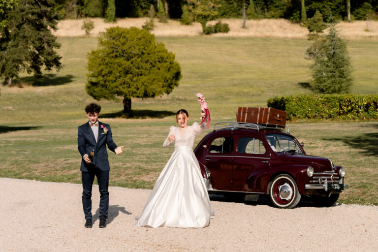 Photographe mariage Jura : mariés qui célèbrent devant la voiture ancienne dans le parc