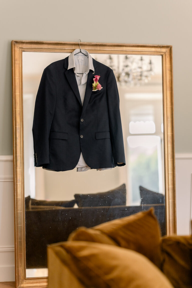 Photographe mariage Jura : costume du marié suspendu devant un miroir doré