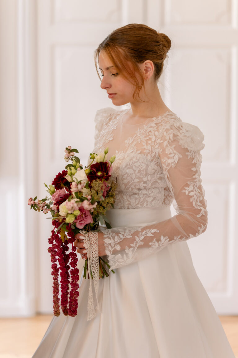 Photographe mariage Jura : mariée en robe à manches en dentelle avec son bouquet