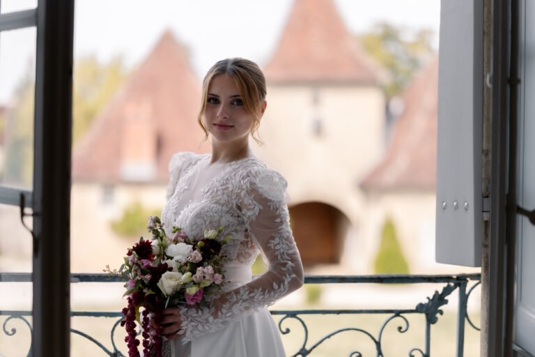 Photographe mariage Jura : mariée sur le balcon, les tours du château en arrière-plan