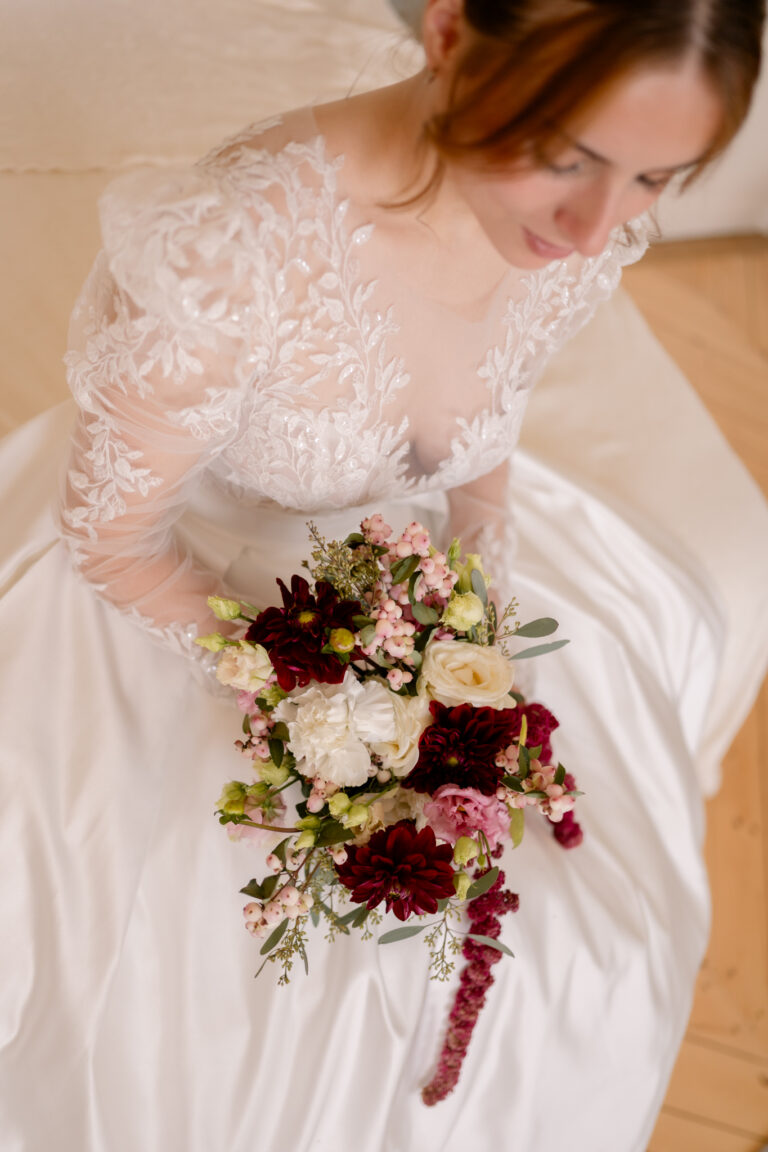 Photographe mariage Jura : mariée qui tient son bouquet bordeaux et blanc