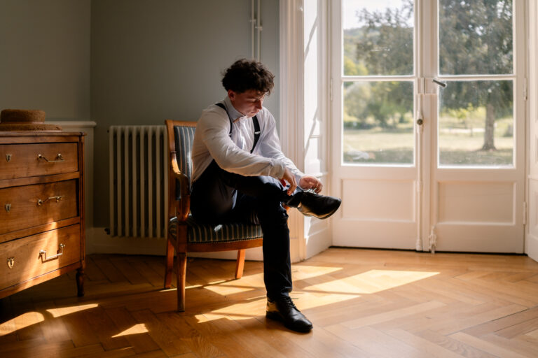 Photographe mariage Jura : marié assis qui lace ses chaussures