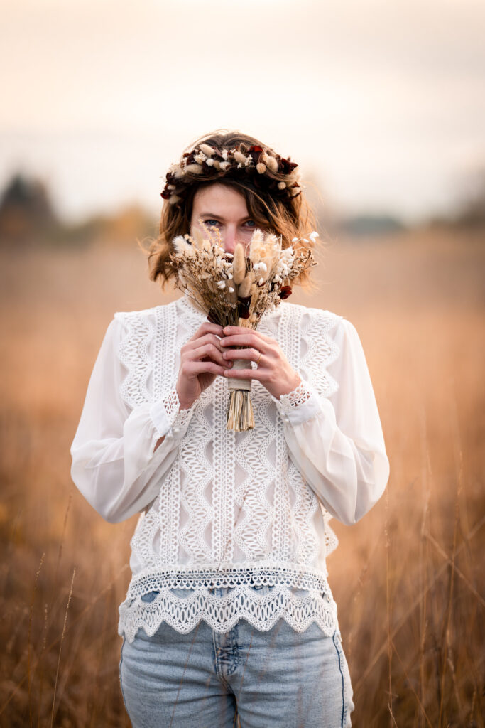 Photographe portrait Morez Jura Genève Lausanne Champagnole Lons-le-Saunier – femme avec une couronne de fleurs tenant un bouquet séché dans les herbes dorées