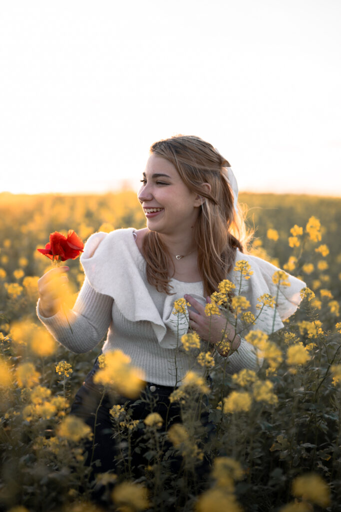 Photographe portrait Morez Jura Genève Lausanne Champagnole Lons-le-Saunier – femme souriante avec un coquelicot dans un champ de colza