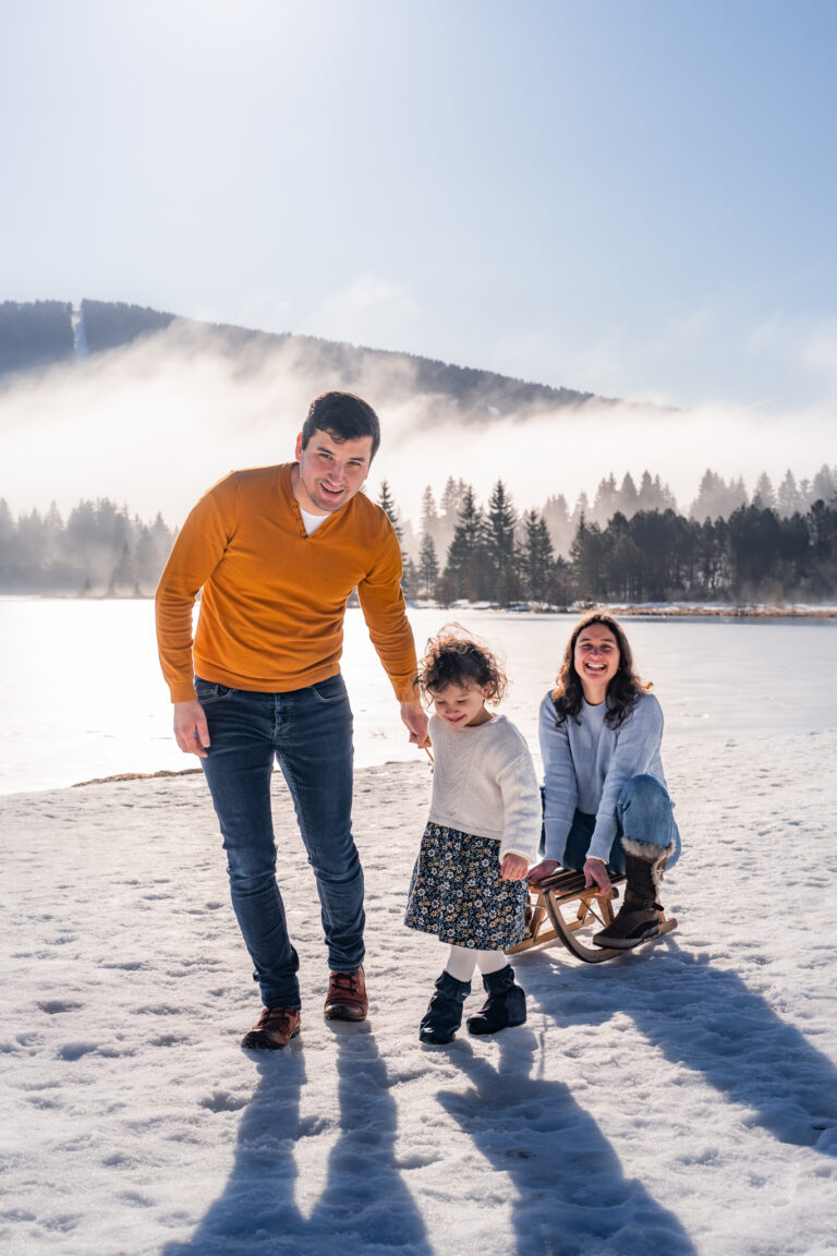 Séance photo famille dans le Haut-Jura : papa et ses filles marchant avec une luge dans la neige
