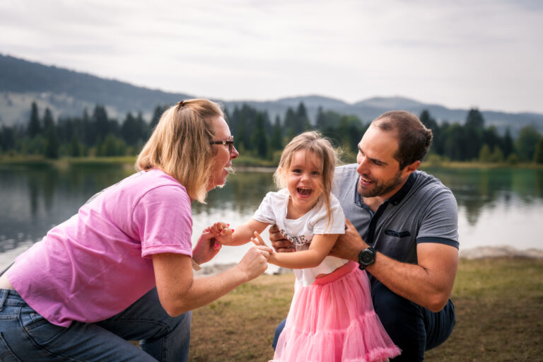 Séance photo famille dans le Haut-Jura : parents jouant avec leur petite fille au bord d’un lac