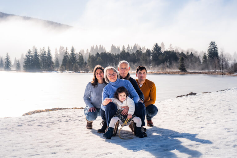 Séance photo famille dans le Haut-Jura : famille réunie sur une luge au bord d’un lac enneigé