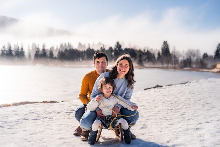 Séance photo famille dans le Haut-Jura : famille sur une luge au bord d’un lac enneigé