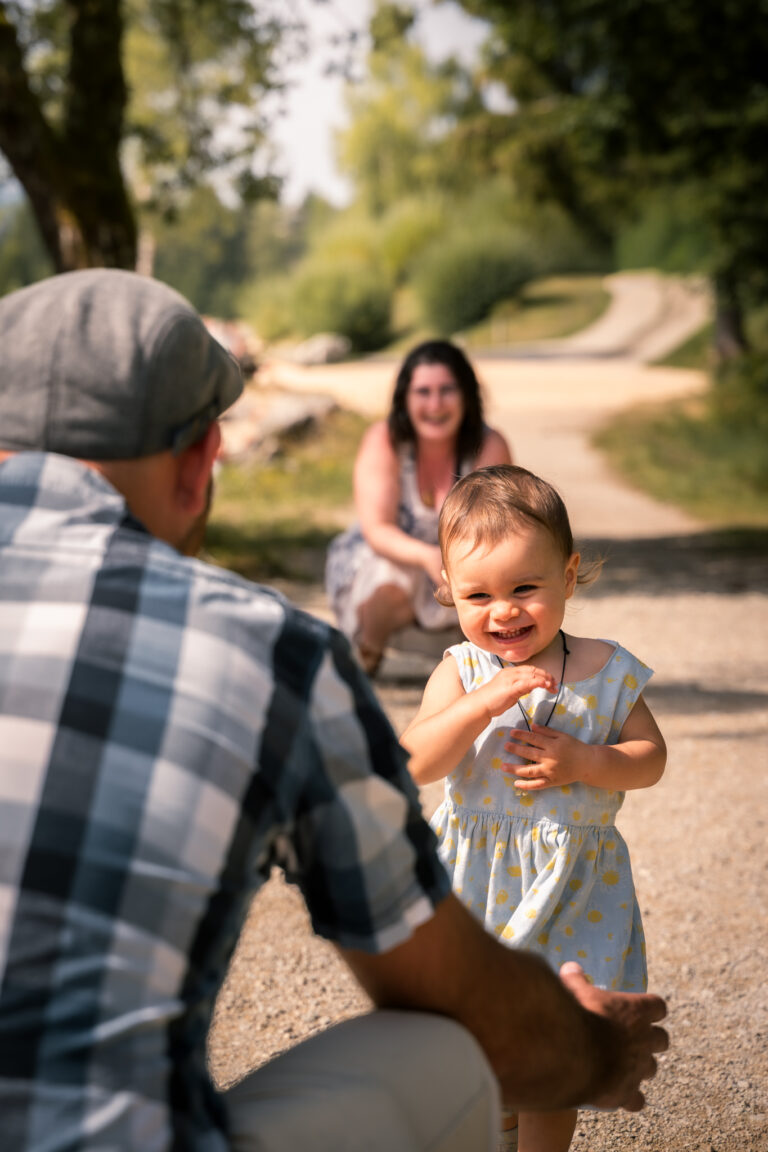 Séance photo famille dans le Haut-Jura : petite fille souriante avec son papa sur un chemin ensoleillé