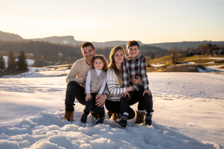 Séance photo famille dans le Haut-Jura : famille réunie dans la neige face aux montagnes