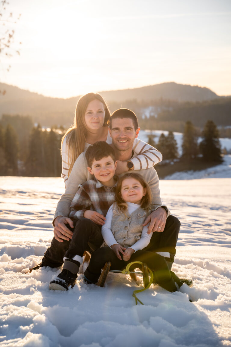 Séance photo famille dans le Haut-Jura : famille blottie dans la neige au coucher du soleil