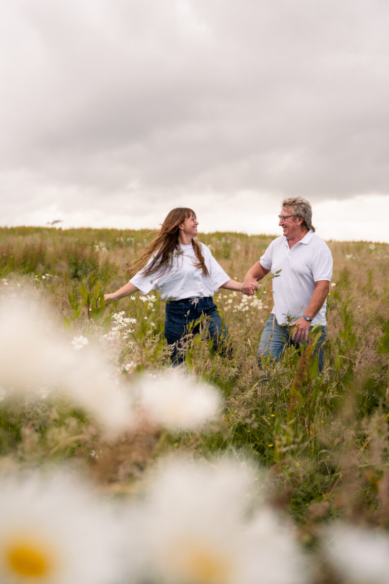 Séance photo famille en Normandie : papa et sa fille main dans la main dans un champ fleuri