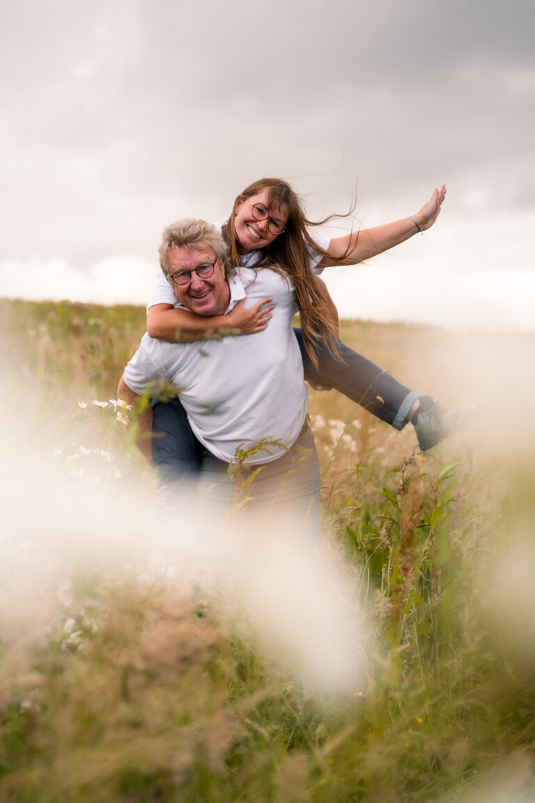 Séance photo famille en Normandie : papa portant sa fille sur son dos dans un champ